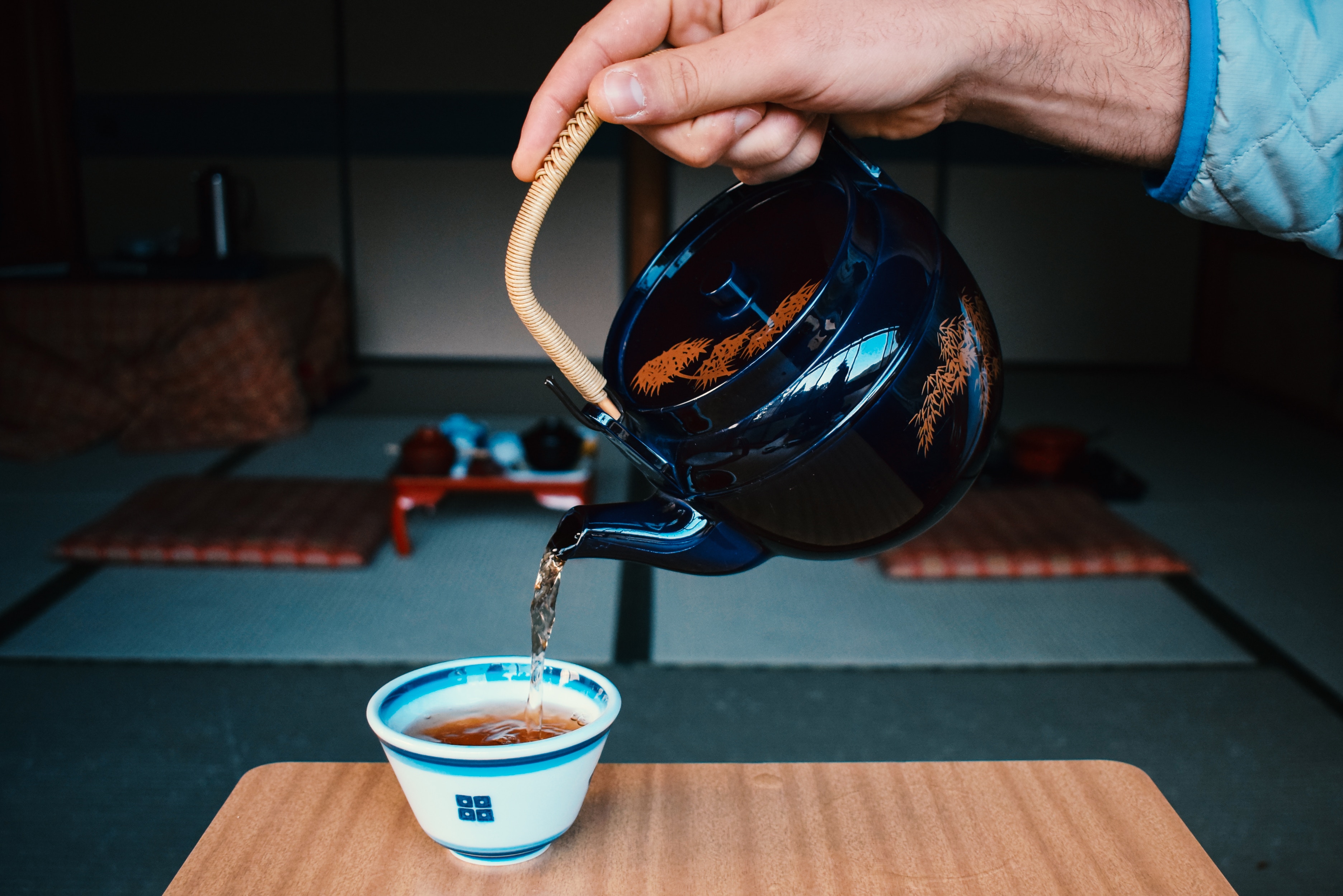 une main verse du thé dans une tasse avec service asiatique conte la tasse de thé conte
